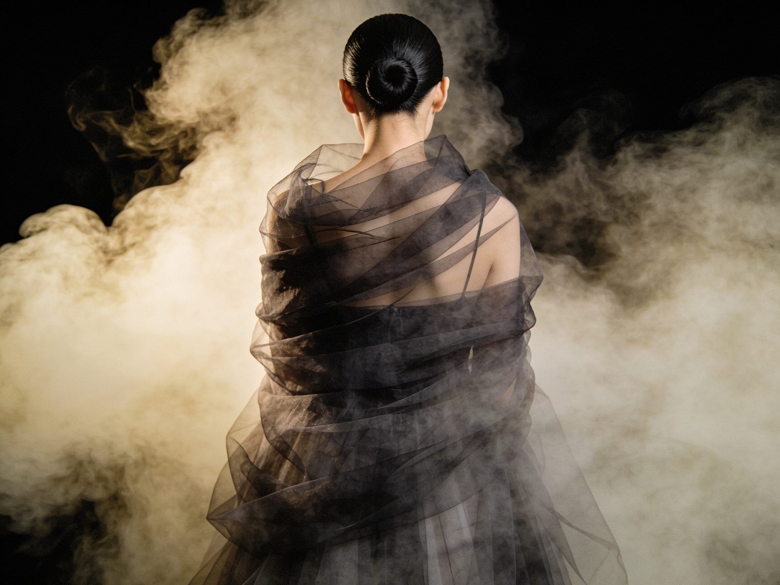 Woman engulfed in flowing charcoal tulle